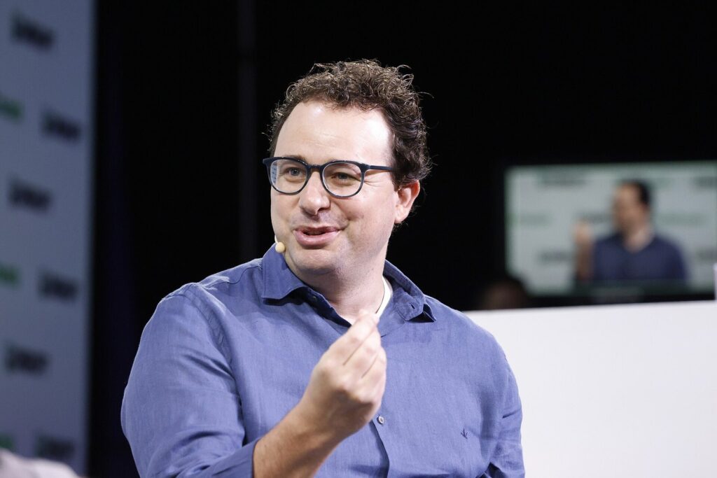 Dario Amodei, de óculos e camisa azul, gesticula enquanto fala no palco do TechCrunch Disrupt 2023