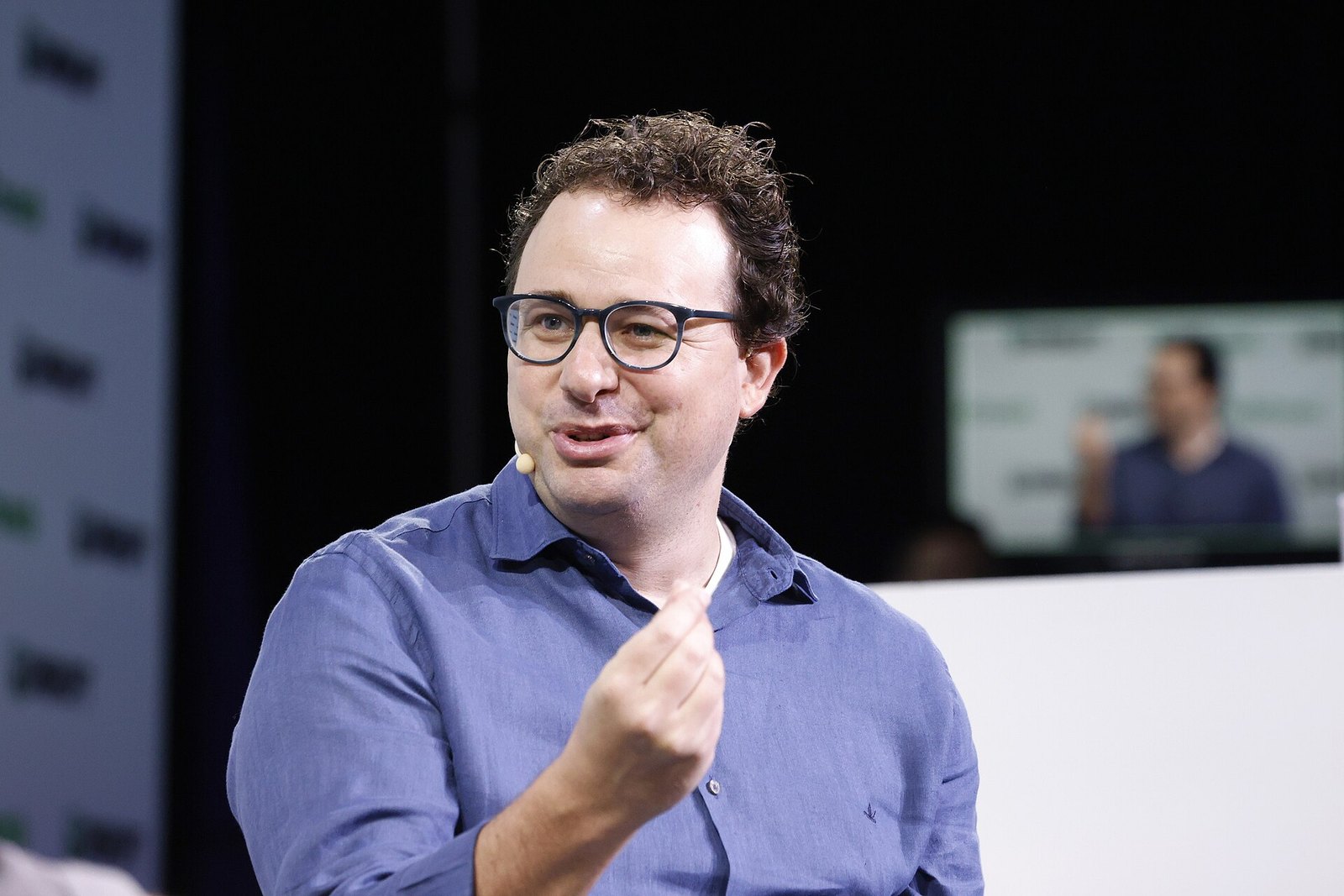 Dario Amodei, de óculos e camisa azul, gesticula enquanto fala no palco do TechCrunch Disrupt 2023