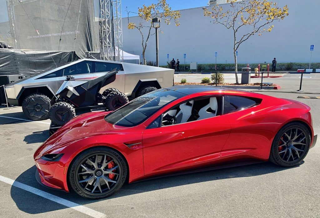 Protótipo vermelho do Tesla Roadster de nova geração estacionado ao lado de um Cybertruck
