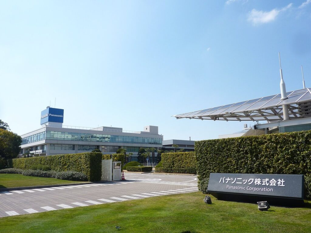 Entrada da sede da Panasonic em Kadoma, Osaka, com placa em japonês e prédio ao fundo